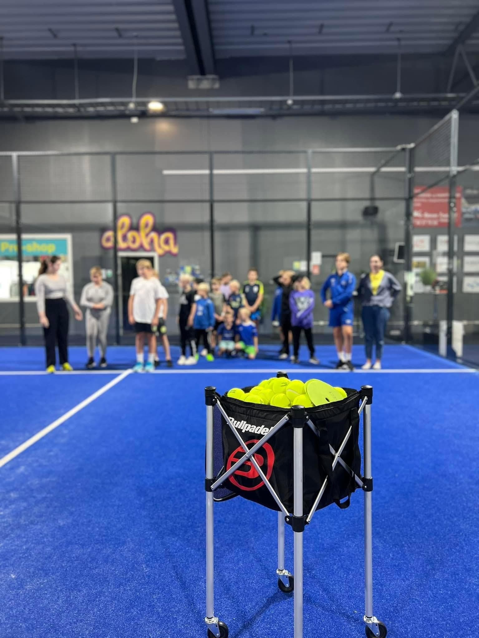 Barn og ungdom samlet på banen under trening på Nivå Padelsenter
